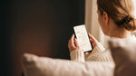 Femme installée sur son canapé, qui consulte l'app Mon rituel CacaoCare sur son téléphone