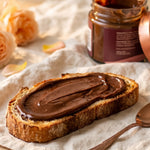 Tartine garnie de pâte à tartiner Équilibre 40+, avec le pot CacaoCare en arrière-plan