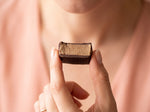 Une femme tient entre ses doigts une bouchée de chocolat noir CacaoCare